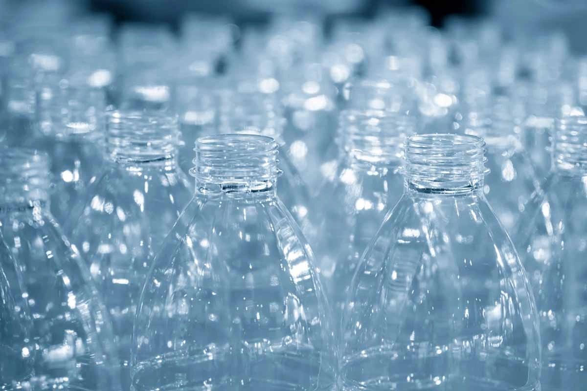 Rows of clear PET bottles on a production line in blue light